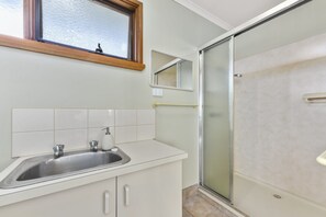 A bathroom with a shower, a sink, and a mirror. - Aireys 15 (Aireys Inlet)