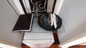 A kitchen with a glass countertop, a white appliance, and a decorative plate with a black rim. - L'Atelier | Vedi Napoli ai tuoi piedi  (Napoli)