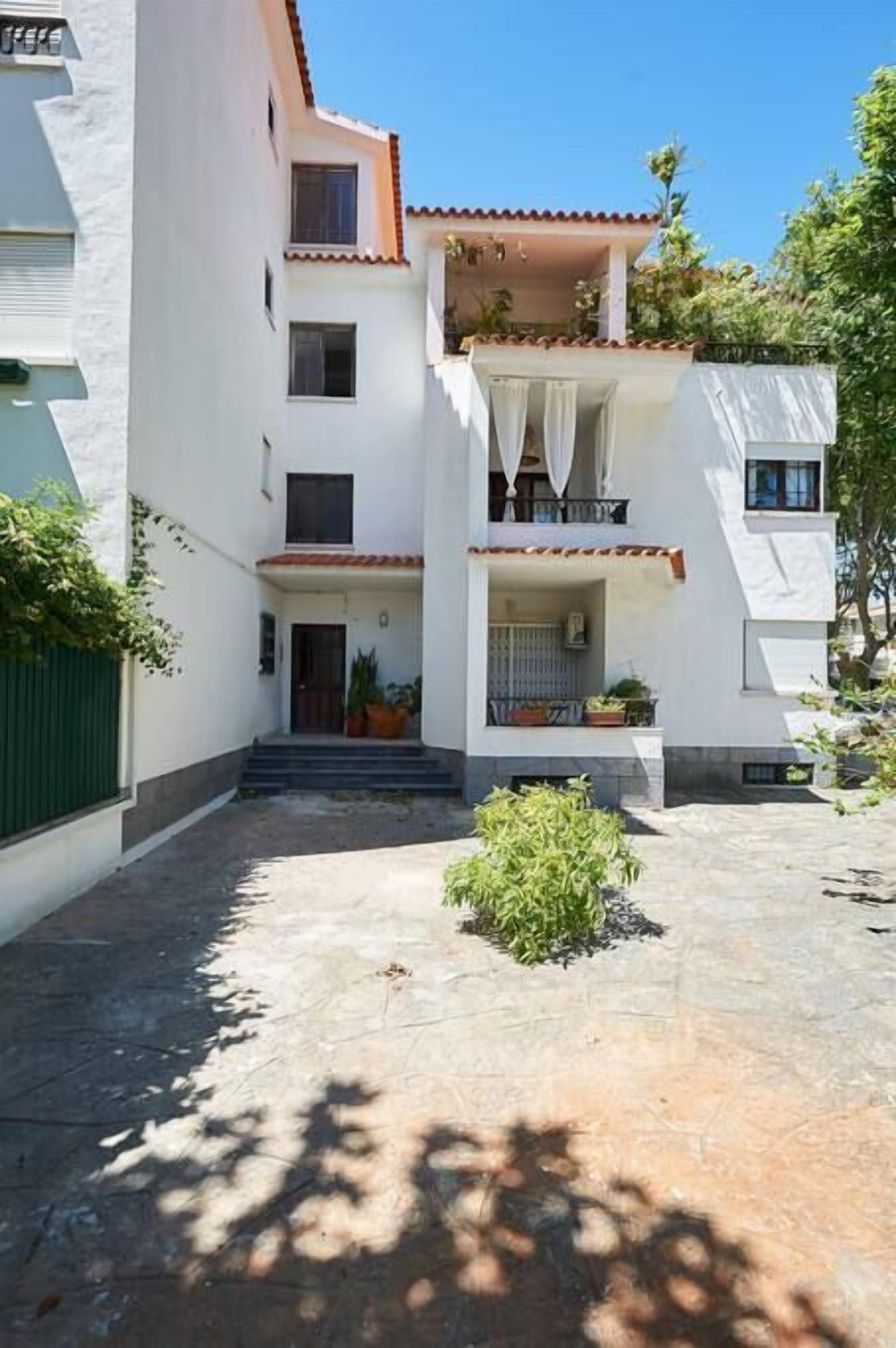 A two-story building with a courtyard, balconies, and potted plants.