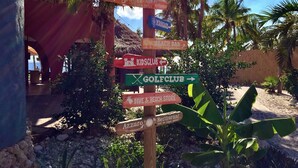 A wooden signpost with multiple directional signs pointing to various amenities such as a golf club, beach bar, and restaurant. - Fully renovated Tropical 3-bdr Villa at Blue Bay Resort, at beach and pool!!! (Blue Bay)