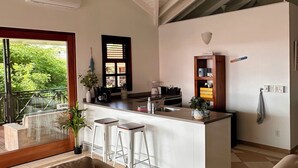 A modern kitchen with a central island, bar stools, and a built-in refrigerator. - Fully renovated Tropical 3-bdr Villa at Blue Bay Resort, at beach and pool!!! (Blue Bay)