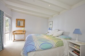A bedroom with a bed, bedside table, lamp, and a window with curtains.
