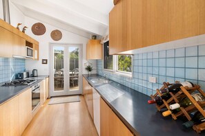 A modern kitchen with wooden cabinets, a stainless steel sink, and a wine rack.