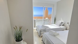 A hotel room with two beds, a potted plant, and a view of the sea and a building. - ⭐ DREAM SEA VIEW PENTHOUSE - LUXURIOUS 3 BEDROOMS ⭐ (Calahonda)