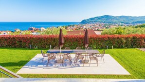 An outdoor dining area with a table and chairs, a view of the sea, and a cityscape in the background. - ViP Panorama, in villa with heated pool (Diano Marina)