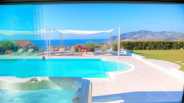 A swimming pool with lounge chairs and a hot tub, surrounded by a patio area with a view of the sea and hills. - ViP Panorama, in villa with heated pool (Diano Marina)