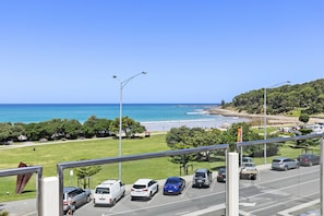 Ein Parkplatz mit Fahrzeugen, einem klaren Himmel und Blick auf Strand und Meer.
