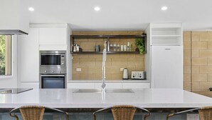 A modern kitchen with a central island, stainless steel appliances, and a brick backsplash. - Lorne Lodge (Lorne)