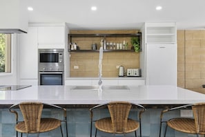 Eine moderne Küche mit Kochinsel, Edelstahlgeräten und einer Backsplash aus Ziegelsteinen.