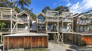 A series of elevated wooden structures with multiple levels, each featuring balconies and large windows, surrounded by trees. - Lorne Lodge (Lorne)