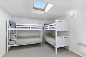 Ein Zimmer mit Etagenbetten, einem Dachfenster und einer Wandleuchte.