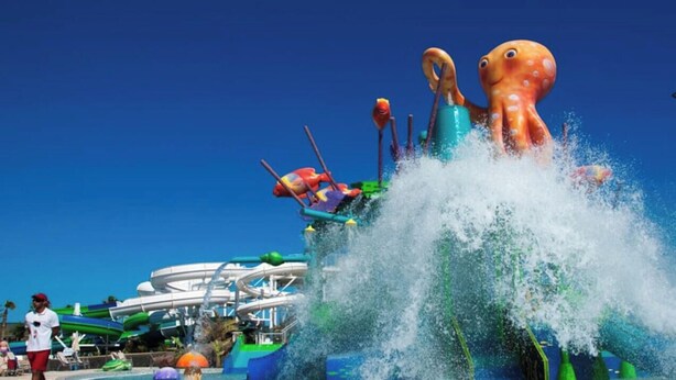 Parque acuático con una gran atracción con forma de pulpo y una piscina de olas.