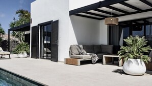Un espacio exterior moderno con piscina, sofá y plantas en macetas.