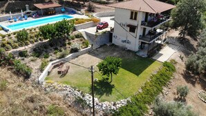 A two-story house with a swimming pool, a balcony, and a garden.