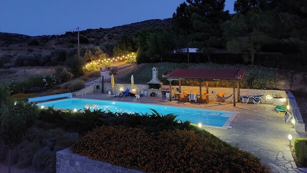 A swimming pool area with a covered patio, stone walls, and string lights.