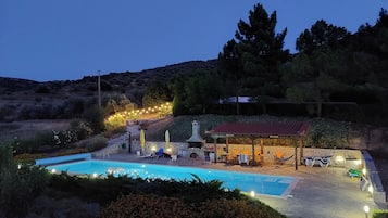 Ein Poolbereich mit überdachter Terrasse, Steinwänden und Lichterketten.