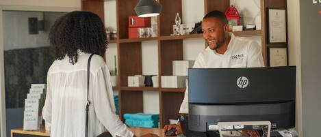 A reception desk with an HP computer, a woman standing, and a man sitting behind the desk.