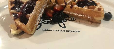 Un piatto di waffle belghe con frutti di bosco e zucchero a velo.