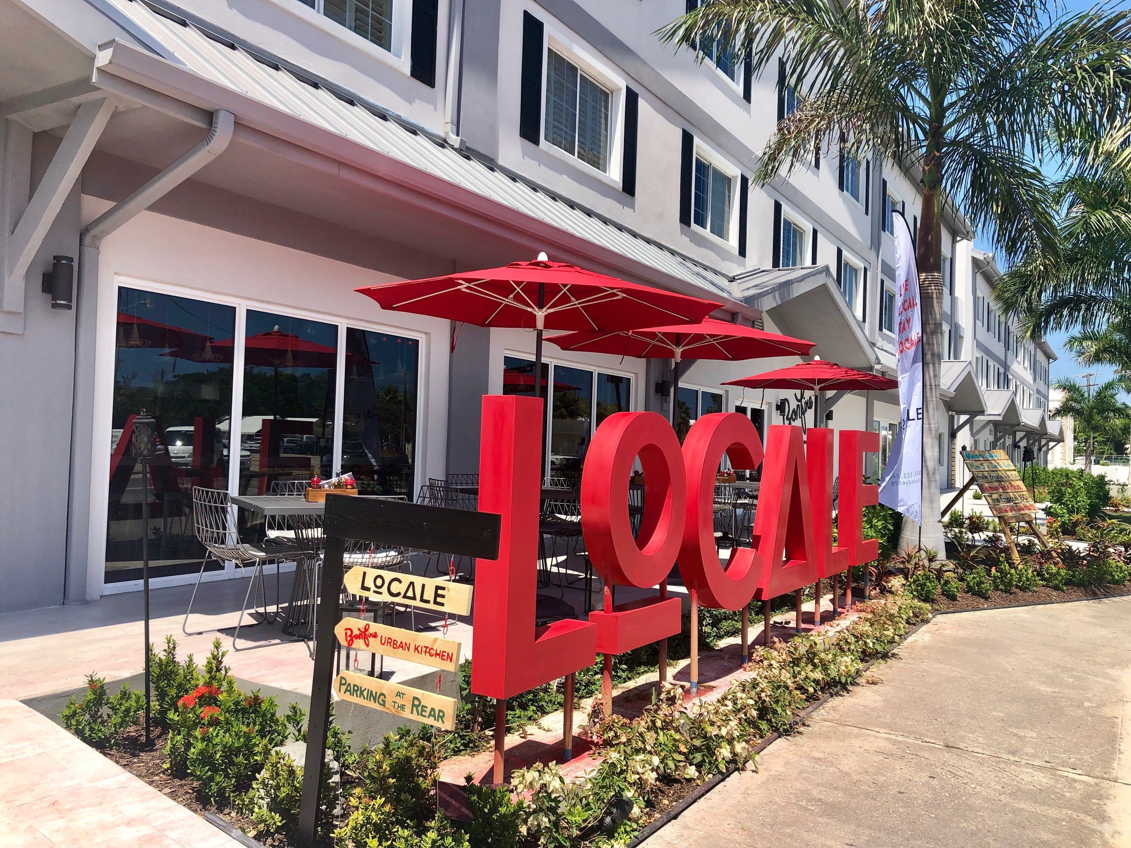 A building with large red letters spelling "LOCALE" and signs indicating "LOCALE," "Urban Kitchen," and "Parking at the Rear."
