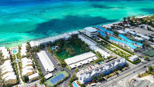 Vista aérea de un resort con varias construcciones, una piscina y una playa.