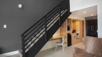 Un interior moderno con una escalera, un escritorio, una silla y un sofá.