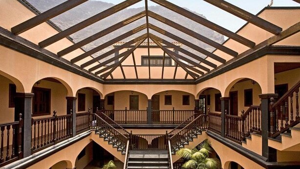 Un atrium à plusieurs niveaux, doté d’un escalier central, de balcons en arc de cercle et d’un plafond en verre.