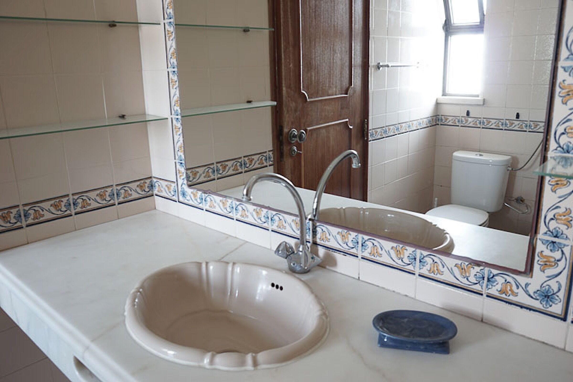 A bathroom with a white sink, a mirror, and a toilet.