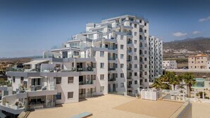Un hôtel moderne à plusieurs étages, doté de balcons et d’un espace piscine.
