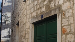 A stone building with a green door and a number '4' sign. - Apartments Optimist (Makarska)