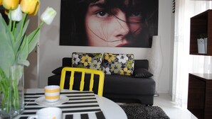 A modern living room with a black and white striped table, a yellow chair, and a black sofa with floral cushions. - Apartments Optimist (Makarska)
