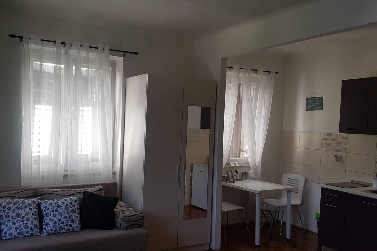 Un espacio habitable compacto con sofá, mesa de comedor y kitchenette.