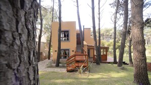 Una casa moderna amb una escala de fusta que condueix a una terrassa, envoltada d'arbres.