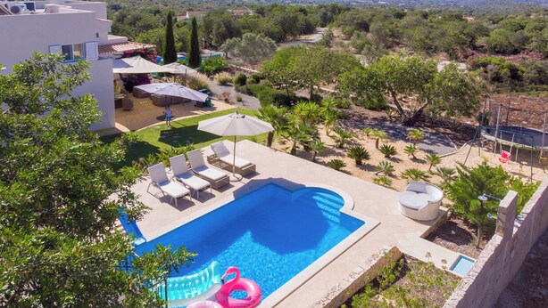 Ein Pool auf dem Dach mit Liegestühlen und Sonnenschirmen, umgeben von Grünflächen und mit Blick auf die Landschaft.