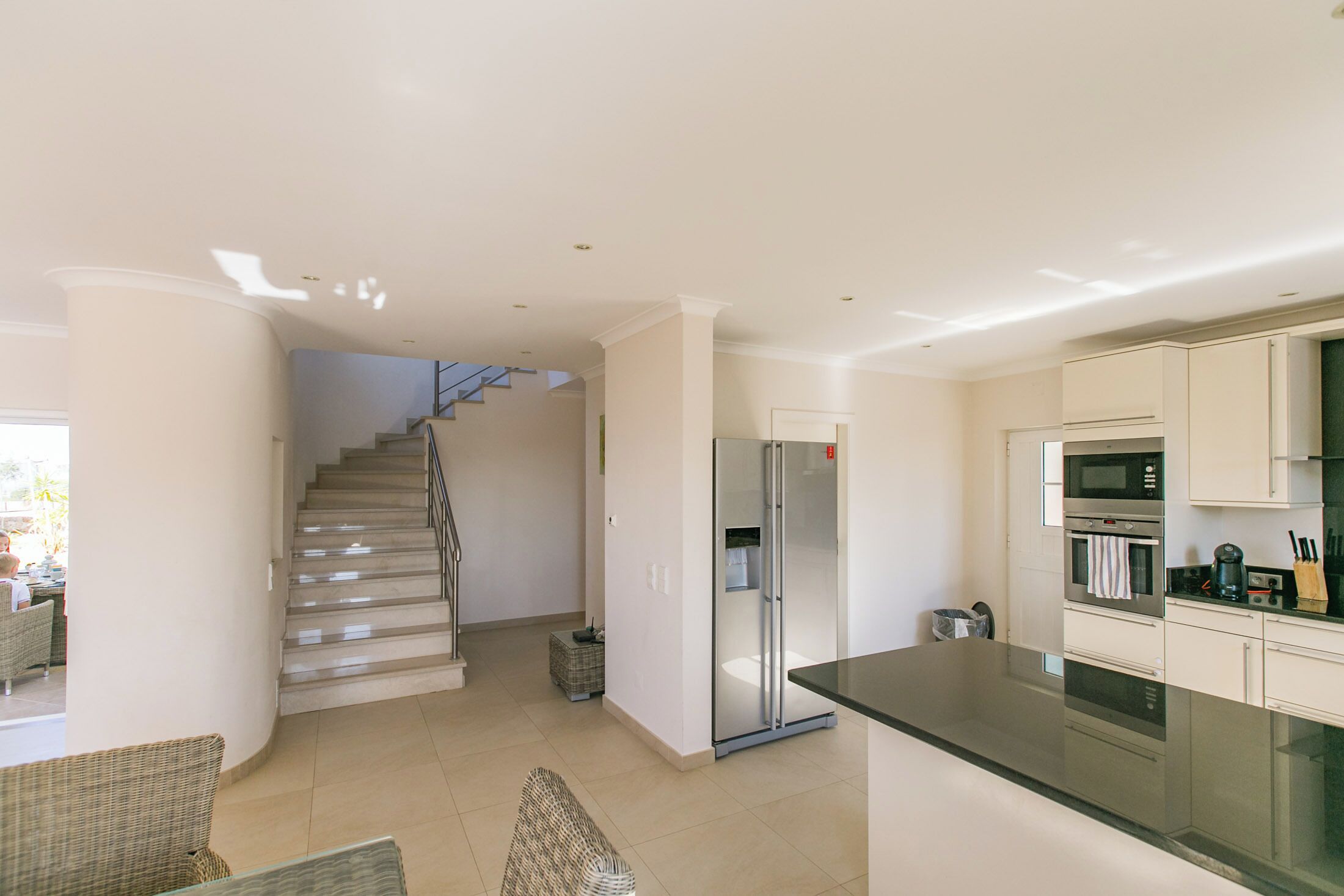 Eine moderne Küche mit Kühlschrank, Backofen und Mikrowelle. Eine Treppe führt zu einer weiteren Ebene.