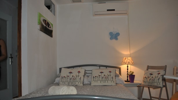 A bedroom with a bed, a chair, a lamp, and a wall-mounted air conditioner. - Apartments Optimist Split (Split)