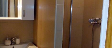 A bathroom with a sink, mirror, and shower.