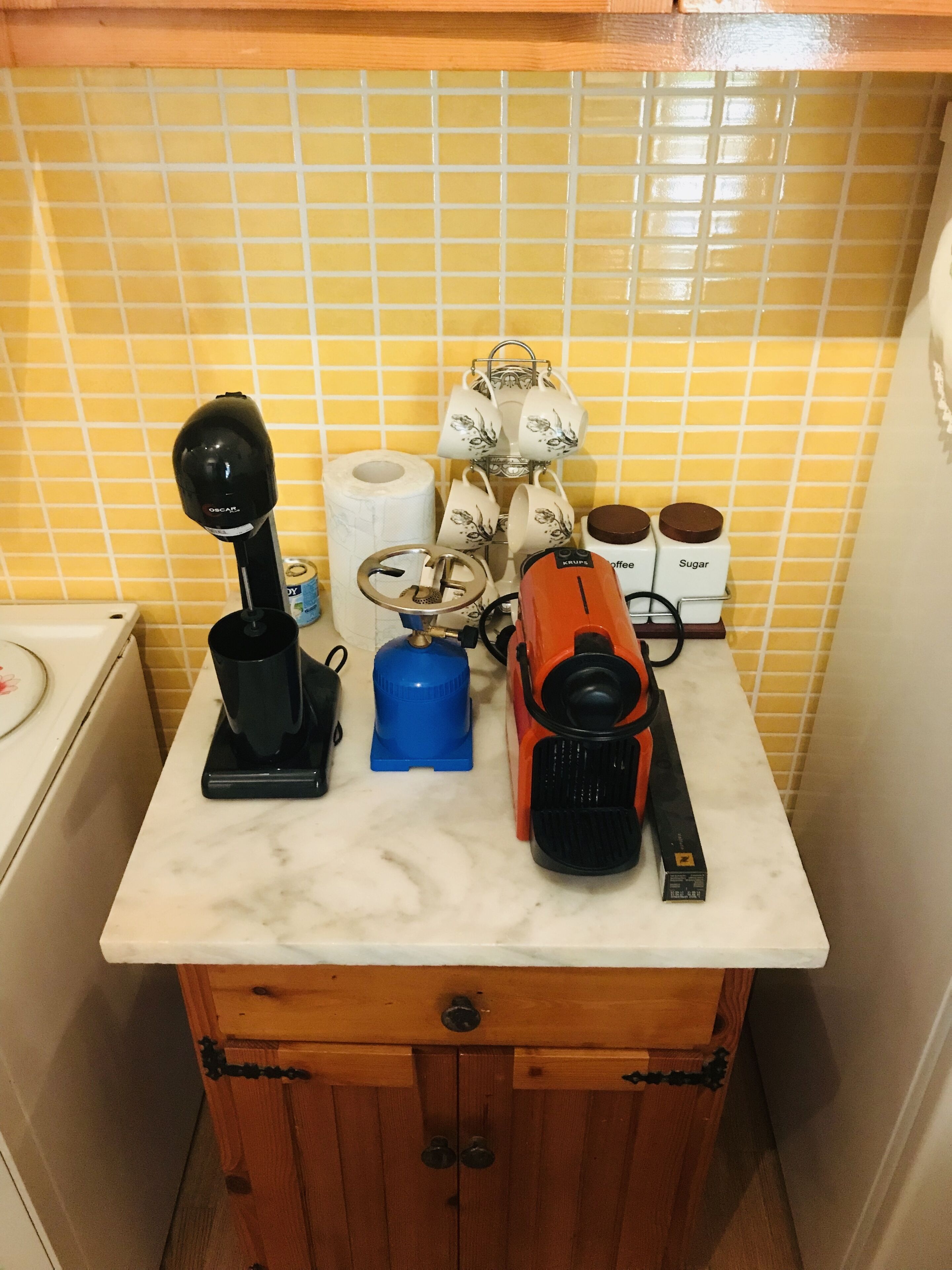 A kitchen counter with a coffee maker, a kettle, a toaster, and a coffee grinder.