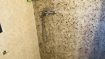 A bathroom with a shower, toilet, and a shelf with toiletries.
