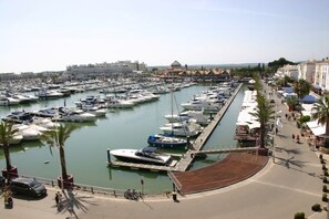 A marina with numerous boats docked, a promenade with palm trees, and buildings in the background. - Quentao Blue Villa, Wifi, AC, Pool (Quarteira)