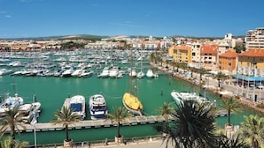 Un port de plaisance où de nombreux bateaux sont amarrés, entouré de bâtiments et de palmiers.