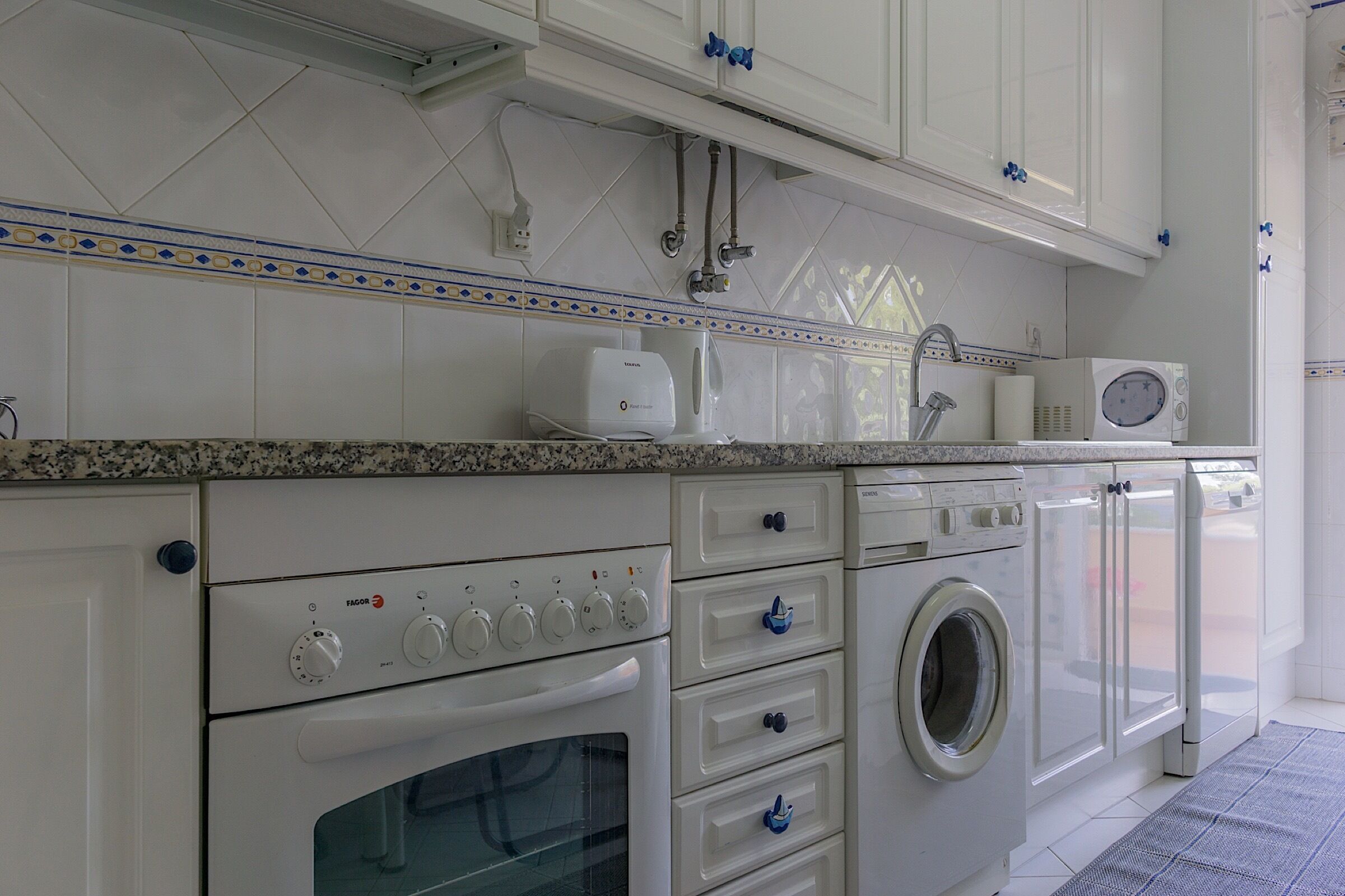A kitchen with a built-in oven, a microwave, and a washing machine.