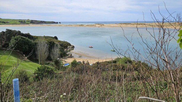 Eine Küstenlandschaft mit Strand, Felsen und wolkenlosem Himmel.