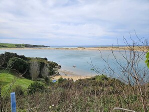 Een kustlandschap met een strand, rotsformaties en een heldere lucht.