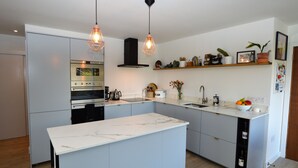 A modern kitchen with a central island, built-in oven, and pendant lighting.