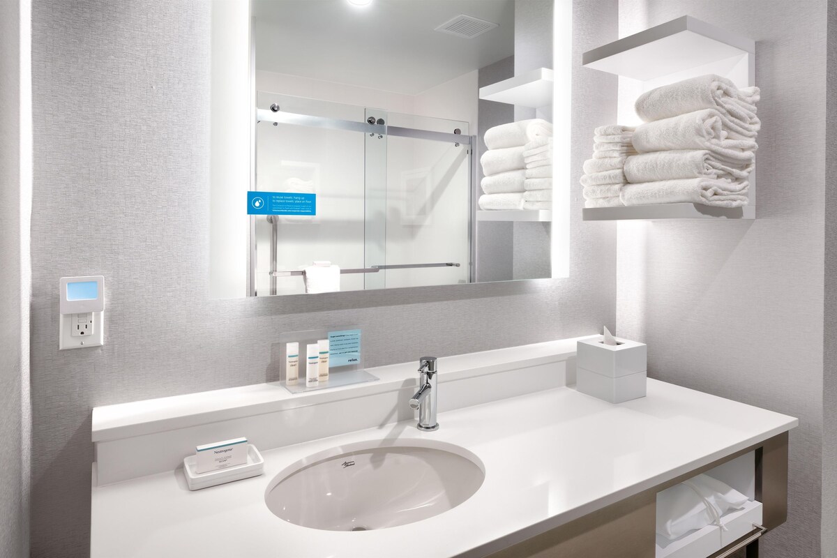 Une salle de bain moderne équipée d’un lavabo, d’un miroir, d’un porte-serviettes et d’articles de toilette.