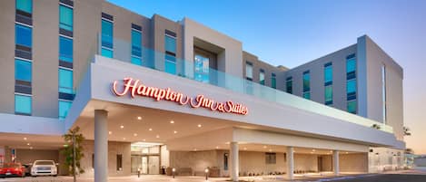 A modern hotel with a prominent sign for Hampton Inn & Suites.