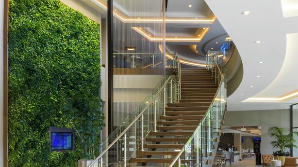 A modern interior with a curved staircase, a green wall, and a reception area.