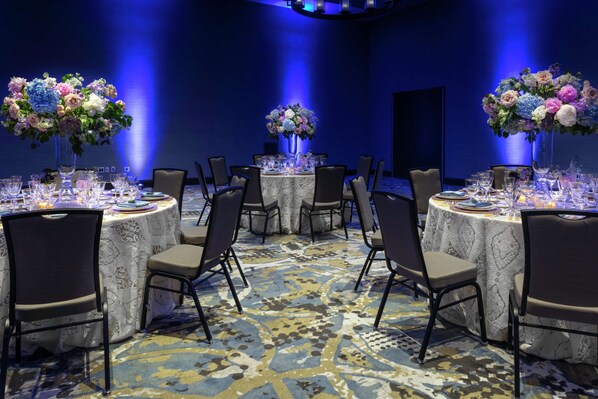 A conference room with round tables, chairs, and floral centerpieces. - Embassy Suites by Hilton Grand Rapids Downtown,MI (Grand Rapids)