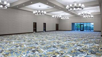 Una habitación amplia con alfombra estampada, varias entradas y ventanas grandes con vistas al exterior.