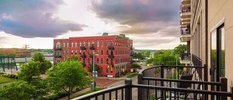 A red brick building with a balcony overlooking a street.